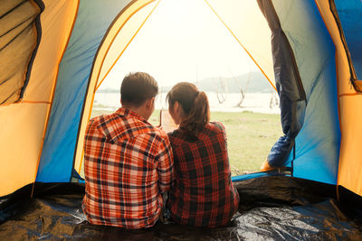 Rear view of couple using digital tablet in tent