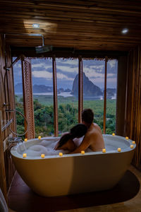 Rear view of couple sitting on window