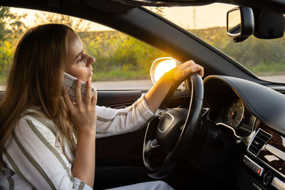 Young woman using mobile phone while sitting in car
