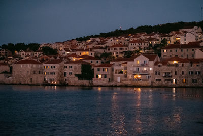 Town by sea against sky at night