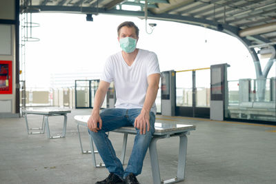 Full length portrait of young man sitting on table