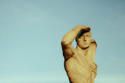 Young man with statue against blue background