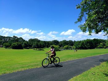 Man with bicycle on field against sky