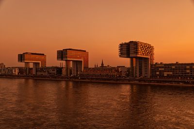 View of city at waterfront - cologne kranhauses against sky at sunset 