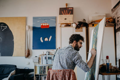 Rear view of man painting on canvas at home