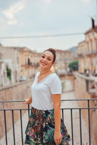 Portrait of smiling young woman standing on balcony