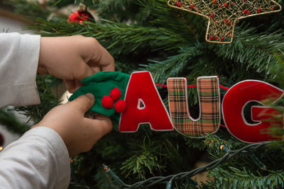 Close-up of woman decorating christmas tree in home