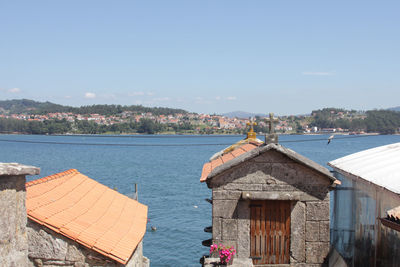 Buildings by sea against blue sky