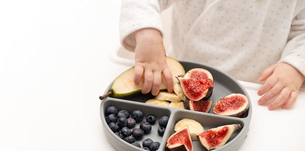 Baby hands taking fruits,berries from silicone plate. copy space.child healthy food 