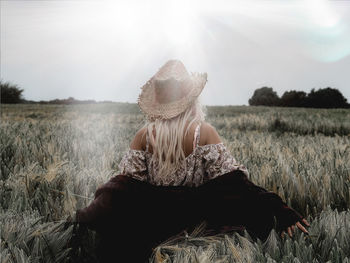 Rear view of woman standing in field against sky