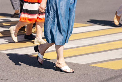 Low section of people walking on zebra crossing