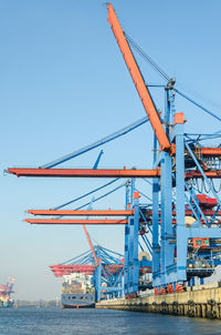 Cranes at pier against clear blue sky