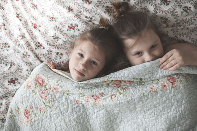 Sister's girls play and cuddle under a blanket, emotions. 