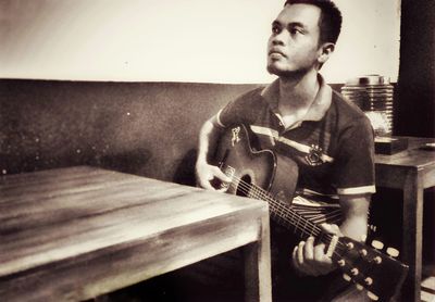 Young man sitting on guitar