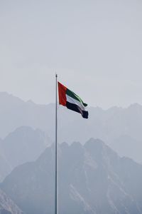 Low angle view of flag on mountain against sky