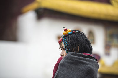 Side view of young woman with braided hair wrapped in blanket