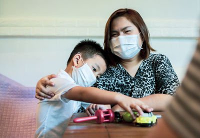 Portrait of mother and son wearing mask sitting at table
