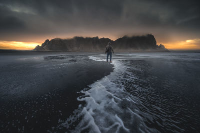 Silhouette man walking on beach against sky during sunset