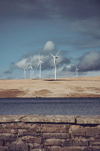 Wind turbines on land against sky