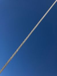 Low angle view of vapor trail against clear blue sky