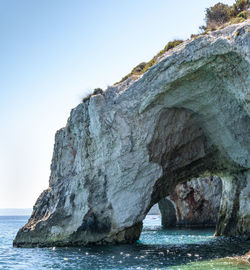 Rock formation in sea against clear sky