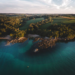 Aerial view of sea by landscape against sky