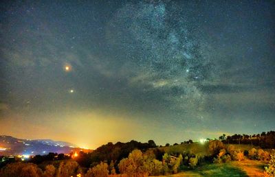 Scenic view of illuminated trees against sky at night