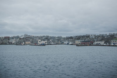 Cityscape by sea against sky