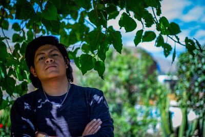 Portrait of young man looking away against plants