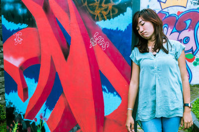 Woman standing against graffiti wall