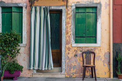 Covered door of aged  house in burano, italy with chair