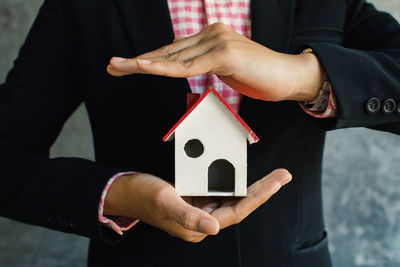 Midsection of businesswoman holding model house