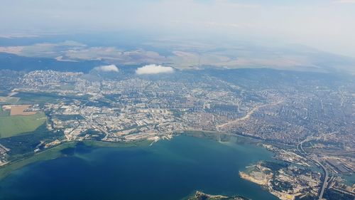 Aerial view of city by sea against sky