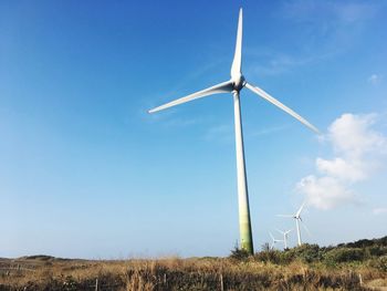 Windmills on field against sky