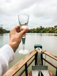 Glass of champagne in hand on the bow of a ship
