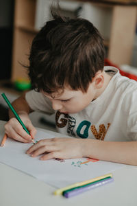 The boy draws with pencils at the kitchen, closeup. high quality photo