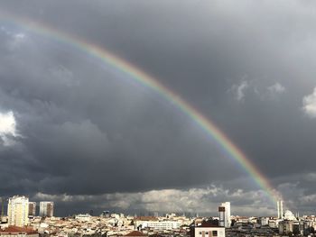 Rainbow over city against sky