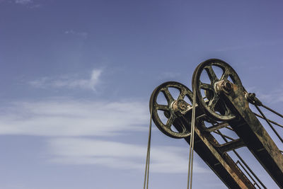 Low angle view of pulley against sky