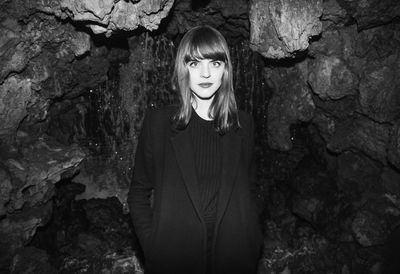 Portrait of young woman standing on rock at night