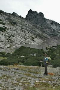 Woman standing on rock by mountains against sky