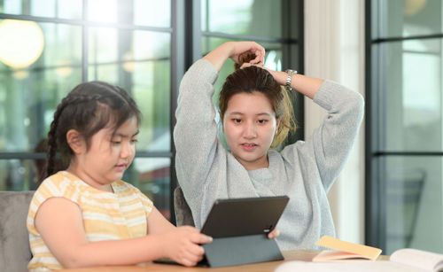 Asian girl studying privately with tutor at home, siblings teaching homework, online learning.