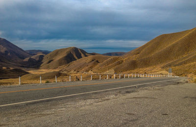 Scenic view of road by mountains against sky