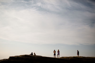 People on rock against sky