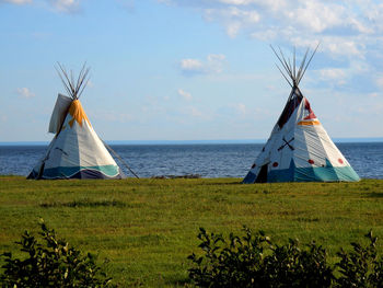 Traditional windmill in sea against sky