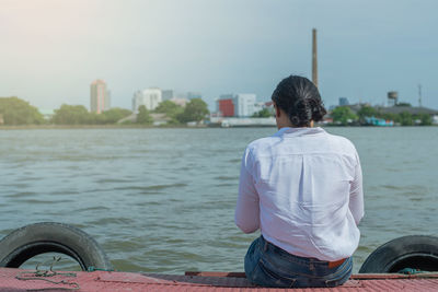 Woman sitting on the harbor alone and looking on the river