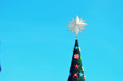 Low angle view of christmas tree against blue sky