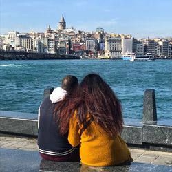 Rear view of woman looking at sea against buildings in city