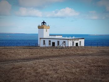 Lighthouse by sea against sky