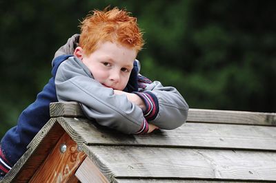 Portrait of cute boy leaning on wood