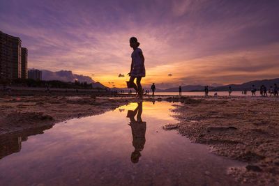 Man standing on beach against sky during sunset